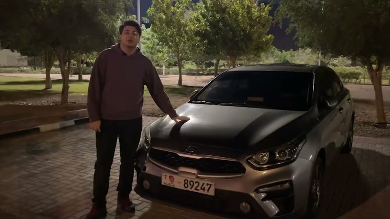Amer standing beside a grey 2020 Kia Cerato at night.